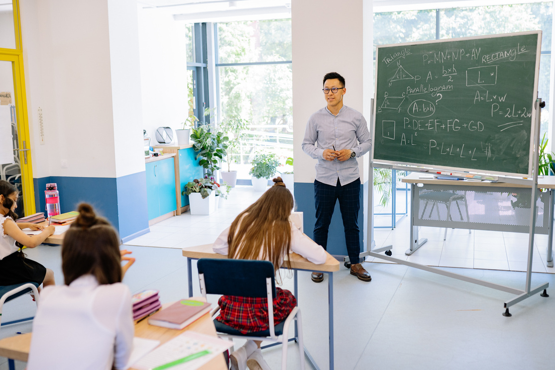 A Man Standing by a Blackboard in a Classroom